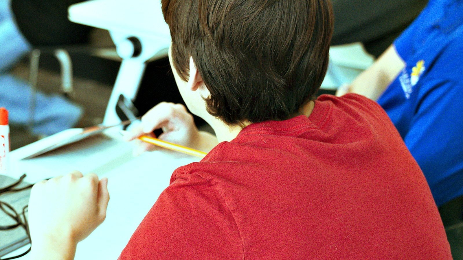 A Goodwin Learning Academy student working at a desk, with noise-reducing headphones beside them