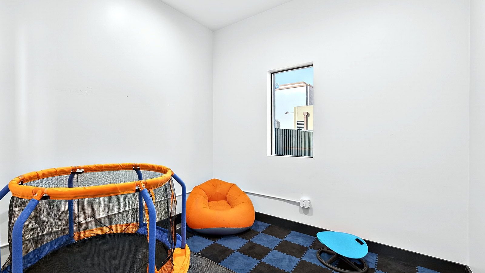 A sensory room at Goodwin Learning Academy with a small trampoline, floor mats and a bean bag